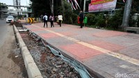 Warga melintas di proyek pelebaran trotoar.
