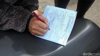 Polisi memberikan surat tilang kepada pengendara yang melanggar lalu lintas.