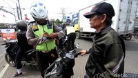 Polisi menilang pengendara sepeda motor yang tidak memakai helm.