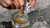 Dimas memasukkan bahan bakar minyak ke dalam toples kaca.