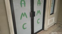 Pintu klinik terkunci rapat dengan tulisan AMC di bagian kacanya. 