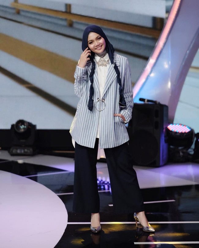 Rina Nose tampil stylish dengan setelan kemeja mullet, celana palazzo hitam, dan striped blazer. Lihat kreasi hijabnya yang membuat penampilan terlihat semakin imut. Ciput ninja menutup leher masih dipakainya pada Agustus 2017. Foto: Dok. Instagram @rinanose16