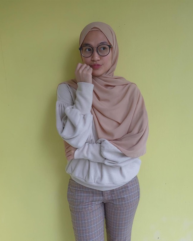 Inge Amelia Nasution tampil kasual memakai stretch pants dan sweater. Ia bergaya simpel dengan jilbab menutup dada menggunakan scarf panjang warna krem.  Foto: Dok. Instagram @ingenst
