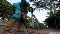 Pekerja membongkar trotoar lama untuk diperlebar dan dipercantik.