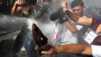 Pendemo yang menolak kendatangan Trump dihalau oleh polisi dengan menyemprotkan air ke massa, Minggu (12/11) waktu setempat. Athit Perawongmetha/Reuters.