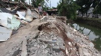 Warga melintasi bangunan liar yang longsor di Bantaran Kali Bintaro, Pesanggrahan, Jakarta, Senin (13/11).