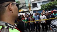Warga menyemut di belakang garis polisi yang dipasang.