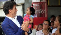 Di tempat itu, Trudeau menggendong seorang anak wanita sambil bergurau dengannya. 