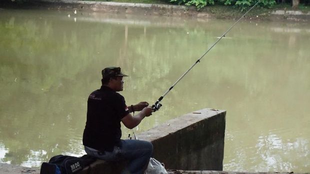 Masyarakat datang ke hutan kota untuk memancing di danau buatan. 