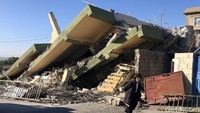 Seorang warga melintas di depan gedung yang rata dengan tanah di Darbandikhan, Provinsi Sulaimaniya, Irak. Reuters/Ako Rasheed.