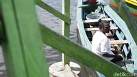 Seorang warga sedang menunggu calon penumpang di perahu.