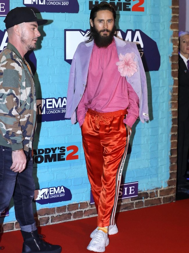 Jared Leto saat menghadiri MTV Europe Music Awards 2017 di London, Inggris, baru-baru ini. Ia memadukan blouse pink dengan jas lavender yang berhiaskan korsase. Track pants atau celana olahraga merah menyalah dipilih sebagai bawahannya. Semuanya rancangan Gucci. (Foto: Getty Images)