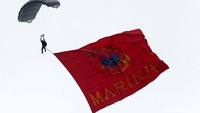 Seorang penerjun membawa bendera Marinir.