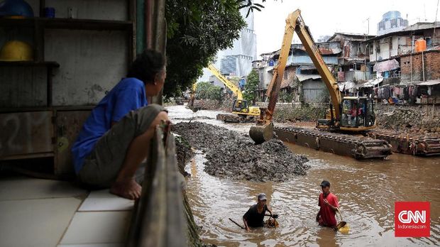 Normalisasi Kali Krukut dengan cara pengerukan sungai, dengan latar bangunan yang menempel kali.