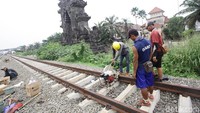 Tiga orang pekerja menyambung rel kereta api.