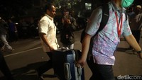 Dua orang itu menenteng koper menuju rumah Novanto.