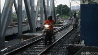 Sejumlah pengendara motor tetap nekat melintas jalur kereta api yang masih aktif di kawasan Petamburan, Jakarta Barat.