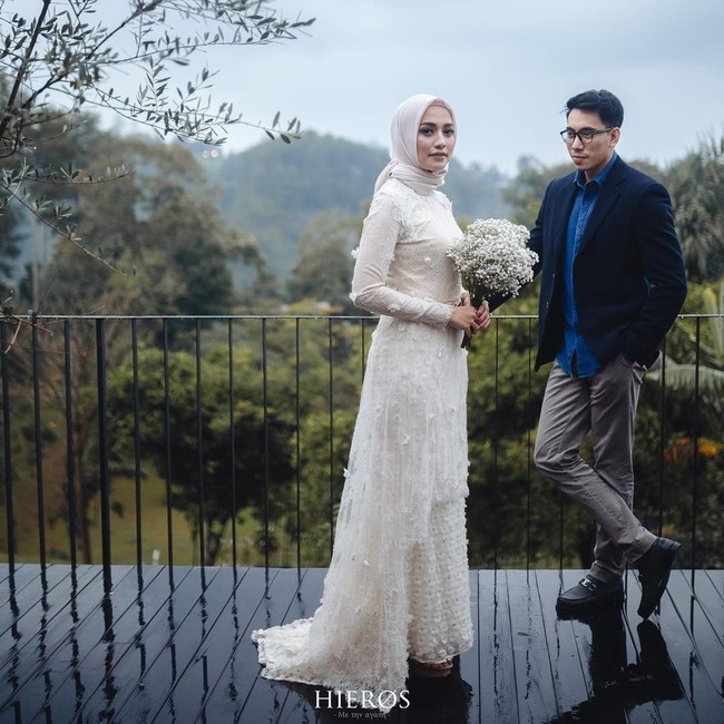 Ada pula pose foto prewedding ketika Mega Iskanti memakai gaun putih panjang dan membawa sebuket bunga. Pakaian mereka tampak resmi dan sang pria yang memakai jas menatap Mega Iskanti sambil tersenyum. Foto: Dok. Instagram