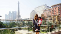 Tidak sendirian, Astrid juga mengajak serta buah hatinya liburan ke Makau. Tampak bangunan yang mirip Menara Eiffel dan gedung pencakar langit Makau di sekelilingnya (missindonesia/Instagram)