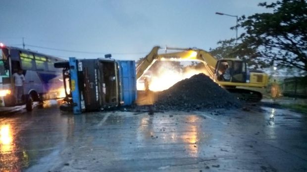 Sebuah backhoe digunakan untuk memindahkan batu bara yang tertumpah