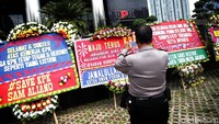 Seorang polisi memotret karangan bungan yang dikirimkan ke gedung KPK, Jakarta, Senin (20/11).