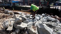 Salah seorang pekerja tengah menghancurkan batu untuk pondasi dinding turap.