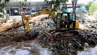 Alat berat terlihat mengangkut batu-batuan untuk pondasi turap.