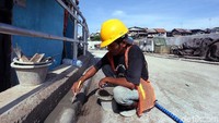 Seorang pekerja merapihkan jalan inspeksi tersebut.  Begini kondisi kawasan Bukit Duri Pangkalan, Tebet, Jakarta Selatan, Senin (20/11/2017). Foto: Rengga Sancaya