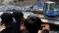 Anak-anak melihat proses pengerukan lumpur.