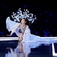 Sebagai model profesional, Ming Xi hebatnya bisa tetap tersenyum walau sedang terjatuh. Ia segera bangun dan membenarkan headpiece bunga besar di kepalanya. Foto: Dok. Reuters