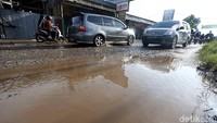 Pengendara mencoba menghindari genangan yang ada di sisi kiri jalan.