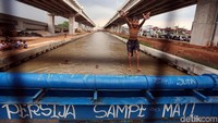 Seorang anak melompat dari pipa yang melintang di atas Kalimalang.