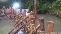 Petugas berseragam biru memasang cerucuk kayu dolken di lokasi bekas tanggul yang jebol. (Foto: Zunita Amalia Putri/detikcom)