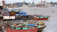 Beberapa perahu melakukan bongkar muat barang di tepi Sungai Musi.