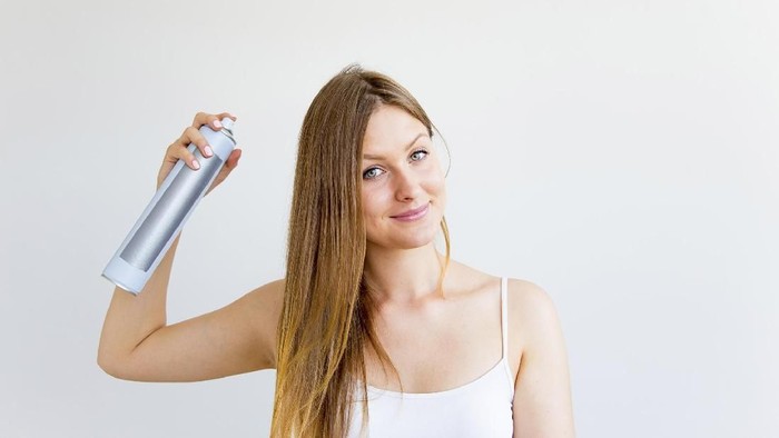 A portrait of a woman styling and drying her hair