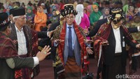 Dia sesekali tampak melirik ke kiri dan kanan mengikuti gerakan tortor para tetua adat.