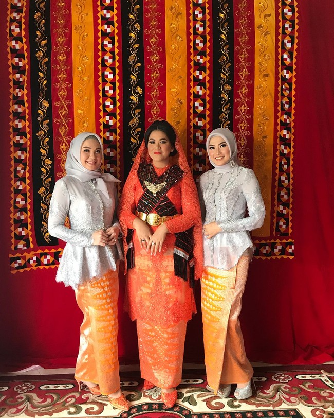 Kahiyang Ayu diapit dua kakak Bobby Nasution, Inge Amelia Nasution dan Poppy Dewinta saat pesta adat. Keduanya tampak cantik dengan gaya hijab simpel dan blouse silver yang dipadukan dengan kain songket oranye bernuansa meriah. Foto: Instagram