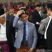 Di saat para tetua terlihat memakai setelan jas hitam dengan kemeja putih yang kancing atasnya dibiarkan terbuka, Gibran memilih sesuatu yang berbeda. Gaya andalan anti-mainstream Gibran terdiri dari kemeja biru berdasi senada yang dibalut jas abu-abu bermotif kotak. Celana bahan biru setumit menjadi pilihan suami Selvi Ananda itu untuk bawahan. Foto: Grandyos Zafna.