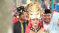 Mereka terus melempar senyum ke arah para tamu undangan yang memenuhi sisi-sisi jalan. Kahiyang membawa dedaunan di genggamannya.