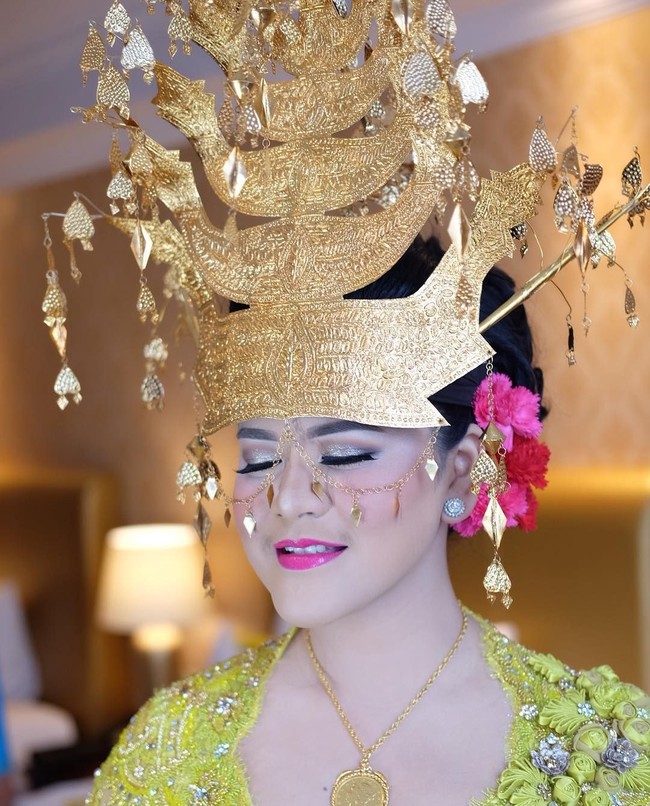 Kepada Wolipop, sang makeup artist mengatakan bahwa makeup Kahiyang disesuaikan dengan adat Mandailing yang harus glamour nan mewah. Tak heran, warna-warna cerah selalu dipakai Kahiyang selama pesta adat di Medan ini. Hari ketiga saat mengenakan kebaya kuning lemon, look make up new retro. Riasan mata yellow-gold sparkle dipertegas dengan eyeliner. Pakai blush on pink, dan lipstik fuschia, ujar Barry Irawan.  Foto: dok. Instagram (Noe_Onhair)