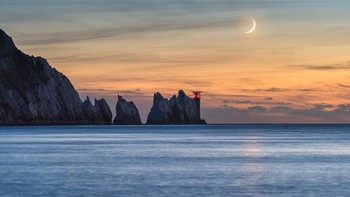 Penampakan bulan sabit 7% di atas langit sore di sekitar mercusuar Needles, Isle of Wight, Inggris. Foto: Ainsley Bennett via PopSugar
