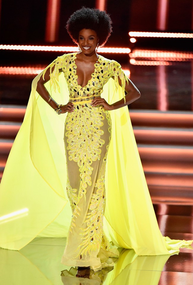 Pilihan warna yang berani dan segar dari Miss Jamaica Davina Bennett. Tren naked dress yang dihiasi ornamen bordir dikemas dramatis dengan lengan cape. Foto: Dok. Getty Images