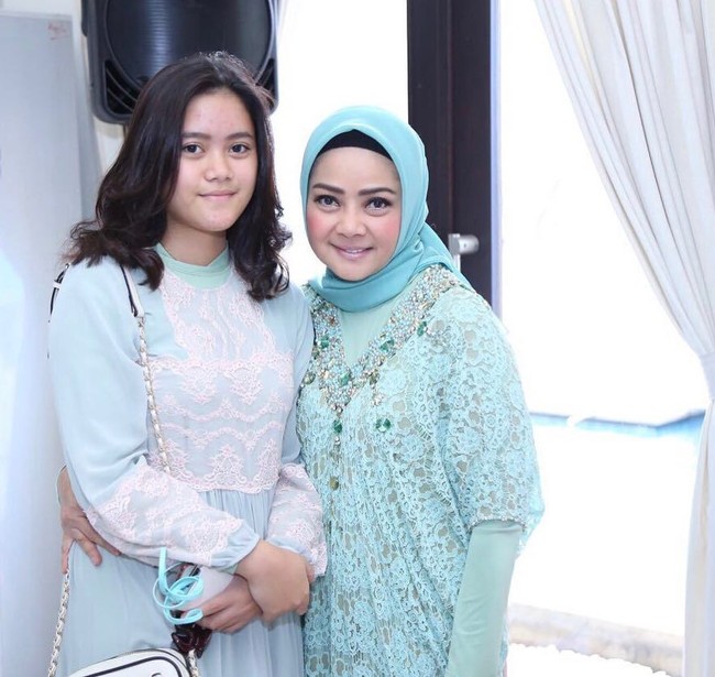 Ini merupakan foto Dewi Ramlan bersama naka gadisnya, Keyyshia. Ia tampil feminin dalam balutan kaftan brokat warna biru muda dan gaya jilbab konvensional serta simpel. Foto: Dok. Instagram @dewiramlan