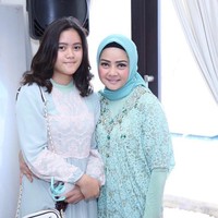 Ini merupakan foto Dewi Ramlan bersama naka gadisnya, Keyyshia. Ia tampil feminin dalam balutan kaftan brokat warna biru muda dan gaya jilbab konvensional serta simpel. Foto: Dok. Instagram @dewiramlan