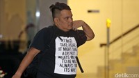Seorang lelaki yang berkaos hitam masuk sambil membawa ransel di punggung. Mereka semua akan diperksa KPK sebagai saksi.