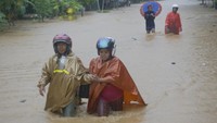 Warga menyeberangi banjir bandang yang memutus jalur lintas selatan Desa Hadiwarno, Pacitan, Jawa Timur, Selasa (28/11)