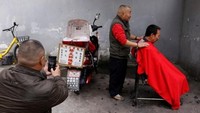 Berbekal motor, skill, kursi lipat dan peralatan cukur, Gaowu melakukan pekerjaannya di pinggir jalanan Chengdu (Tyrone Siu/Reuters)