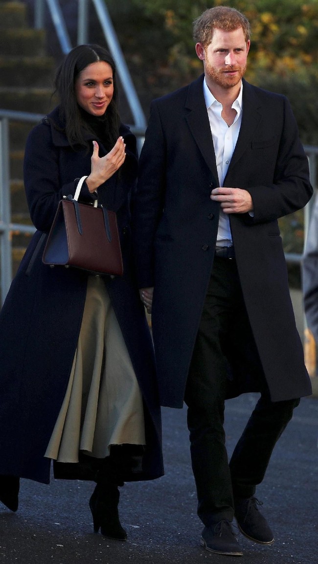 Tas Meghan Markle yang dipakainya saat berkunjung ke Nottingham bersama Pangeran Harry pada awal Desember lalu ternyata juga dianggap tak biasa. Aktris yang membintang serial TV Suits itu menenteng tote bag dari brand asal Skotlandia, Strathburry.  Banyak kalangan menyebut tas dengan pegangan dan tali melanggar protokol kerajaan. Meski bukan protokol resmi, namun menenteng clutch dianggal lebih baik untuk mencegah keluarga kerajaan bersalaman dengan orang-orang tertentu yang akan membuat situasi jadi canggung. Foto: Reuters