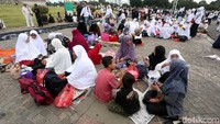 Mereka duduk berkelompok di atas tikar dan koran di sekitar Monas.