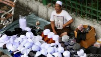 Pedagang peci menunggu calon pembeli.